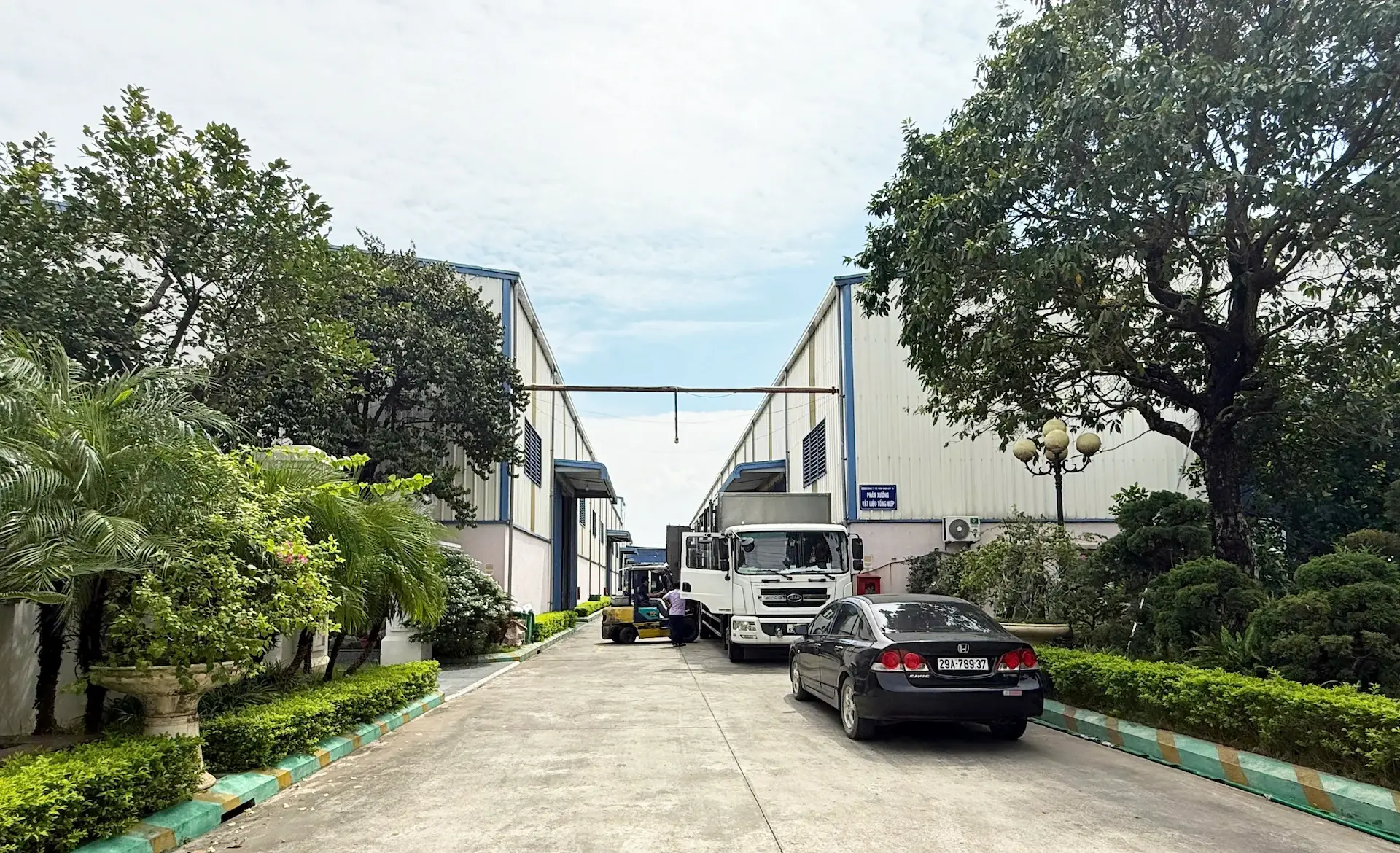 Bright, large-scale pultrusion workshop at 76Plastic showing machinery and stacks of finished yellow and gray FRP profiles.